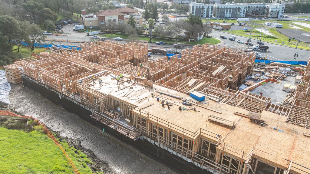 Construction site with partially assembled wooden frame and visible timber elements.`