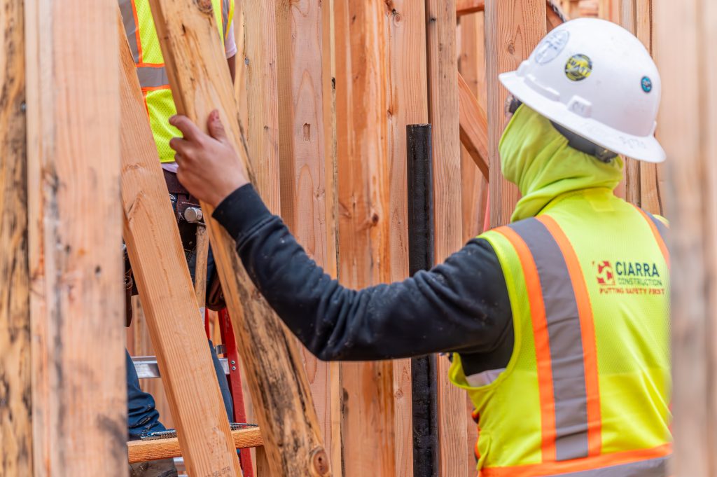 Person installing diagonal braces to strengthen the wooden framework of a house