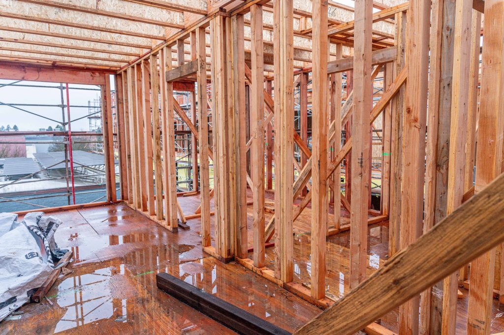 Construction site displaying wooden beams and vertical supports forming the building's frame.