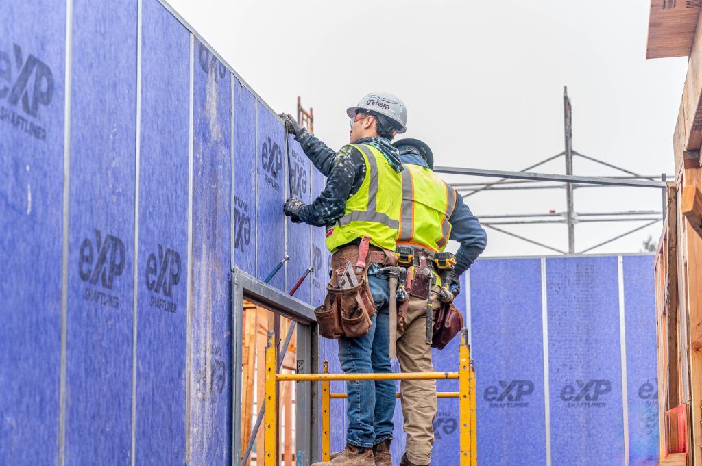 Builder wearing a hard hat and gloves working on wooden floor joists