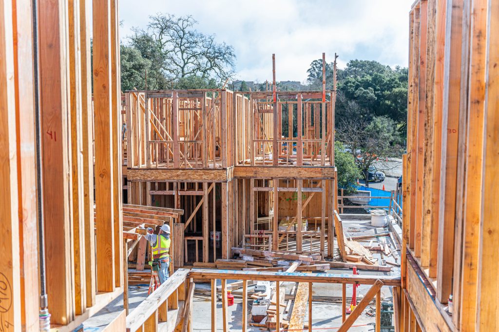 Timber frame under construction, featuring wooden posts and horizontal supports