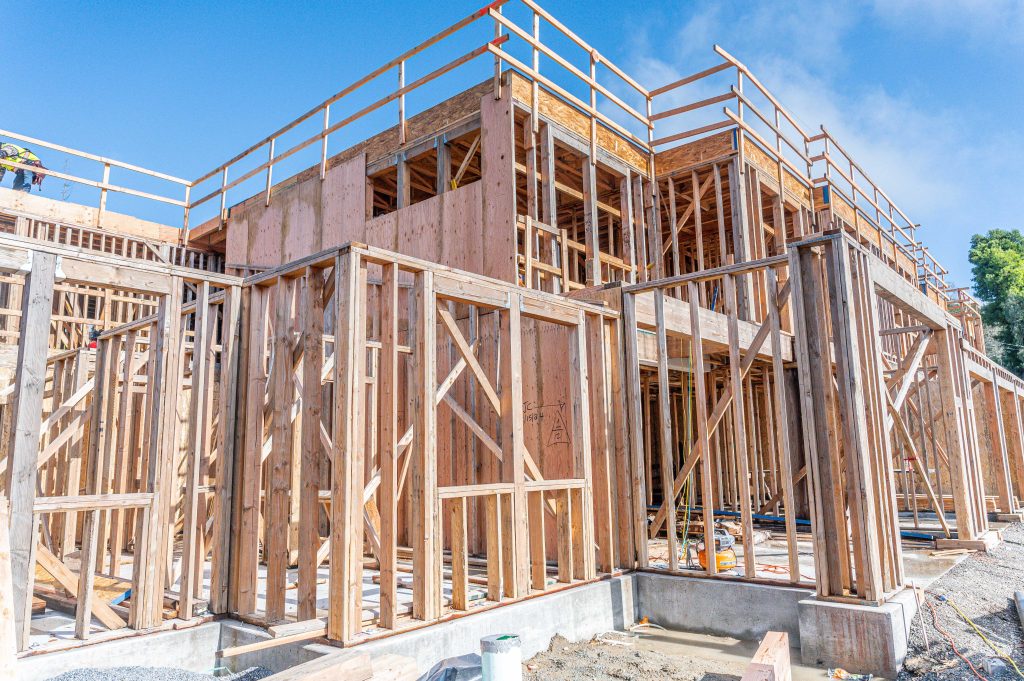 Wooden frame structure with partially installed beams and construction materials.