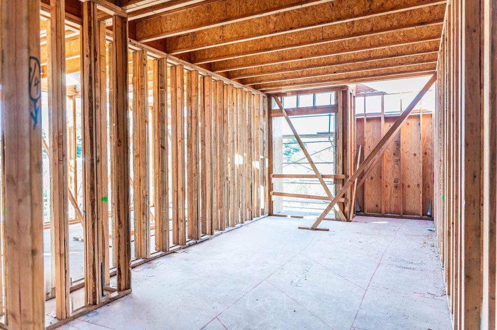 Man using a nail gun to attach wooden planks for constructing a frame