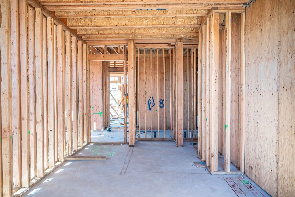 Construction worker aligning wooden beams and securing them with brackets