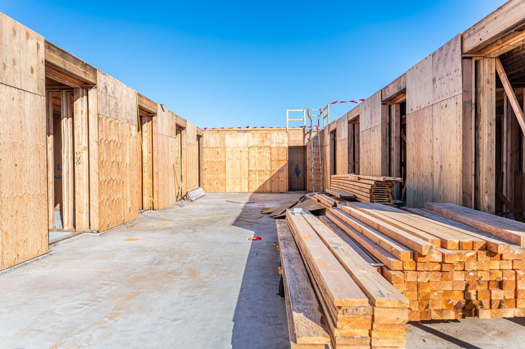 Builder cutting wooden studs to the correct length for wall framing