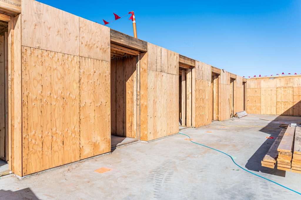 Construction worker using a tape measure to ensure accurate wood placement.