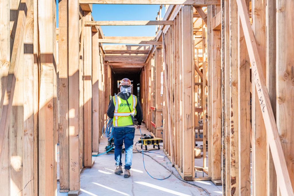 Carpenter in a hard hat assembling wooden rafters for a roof frame.