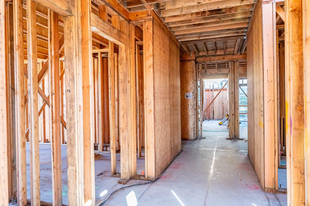 Construction worker installing vertical wooden supports for a wall frame.
