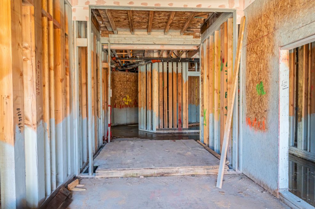 Construction site with a skeletal wooden frame, highlighting vertical posts and horizontal beams