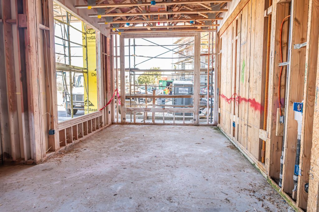 Worker adjusting wooden beams with a crane for a new building frame.