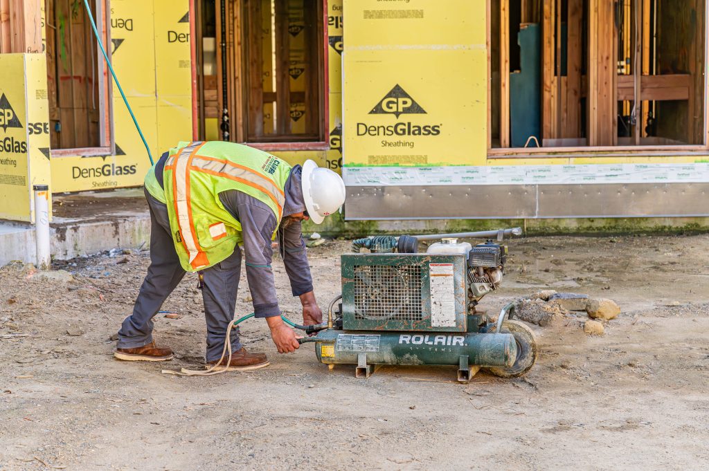 Worker in safety gear assembling and securing wooden frame pieces for constructio
