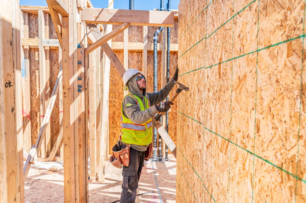 Construction worker with a pencil marking wooden planks for cutting
