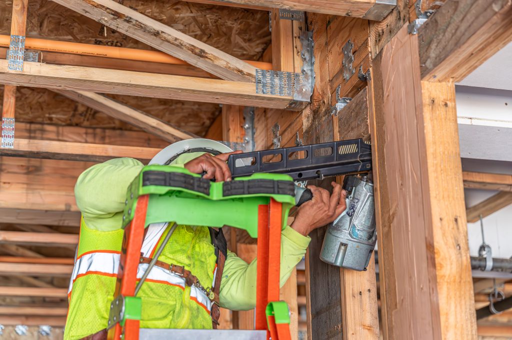 A man working with wooden wall with drill machine