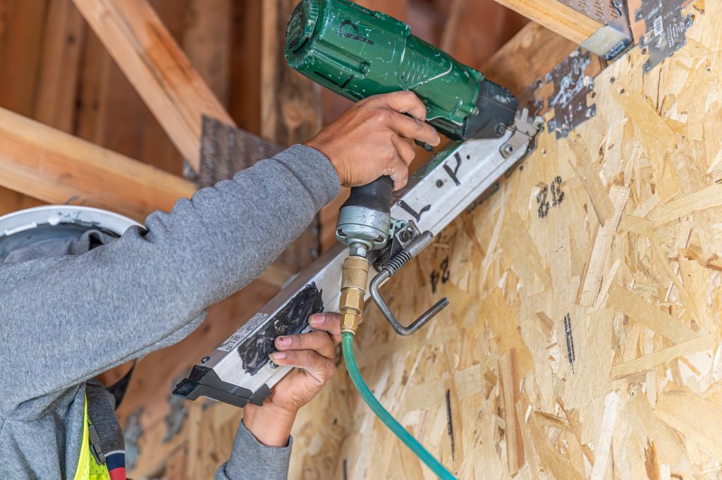 A person working with a machine drill for wooden boards