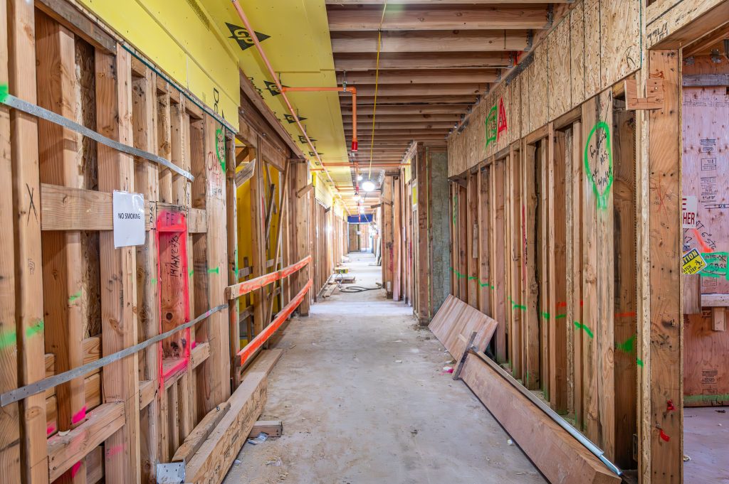 Under-construction timber framework with horizontal and vertical wooden elements in view.