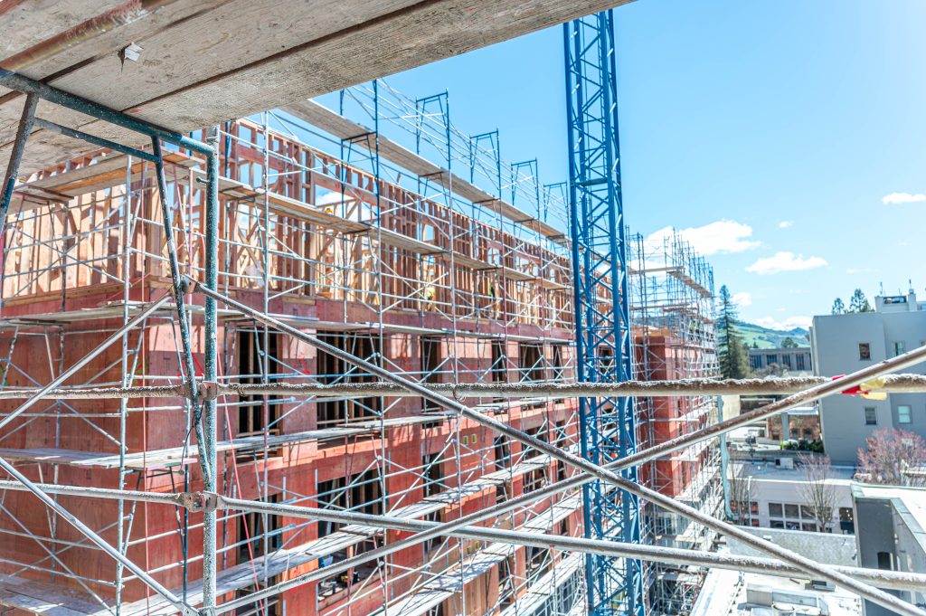 Man carefully positioning wooden trusses for the roof structure of a building