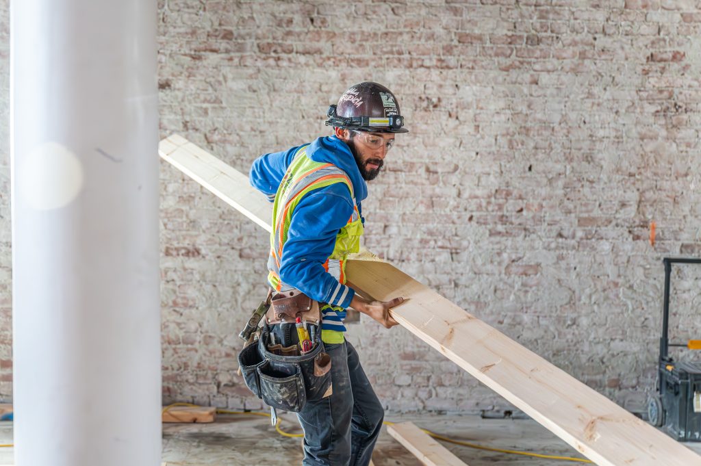 Person cutting wooden studs with a saw to fit into the construction frame