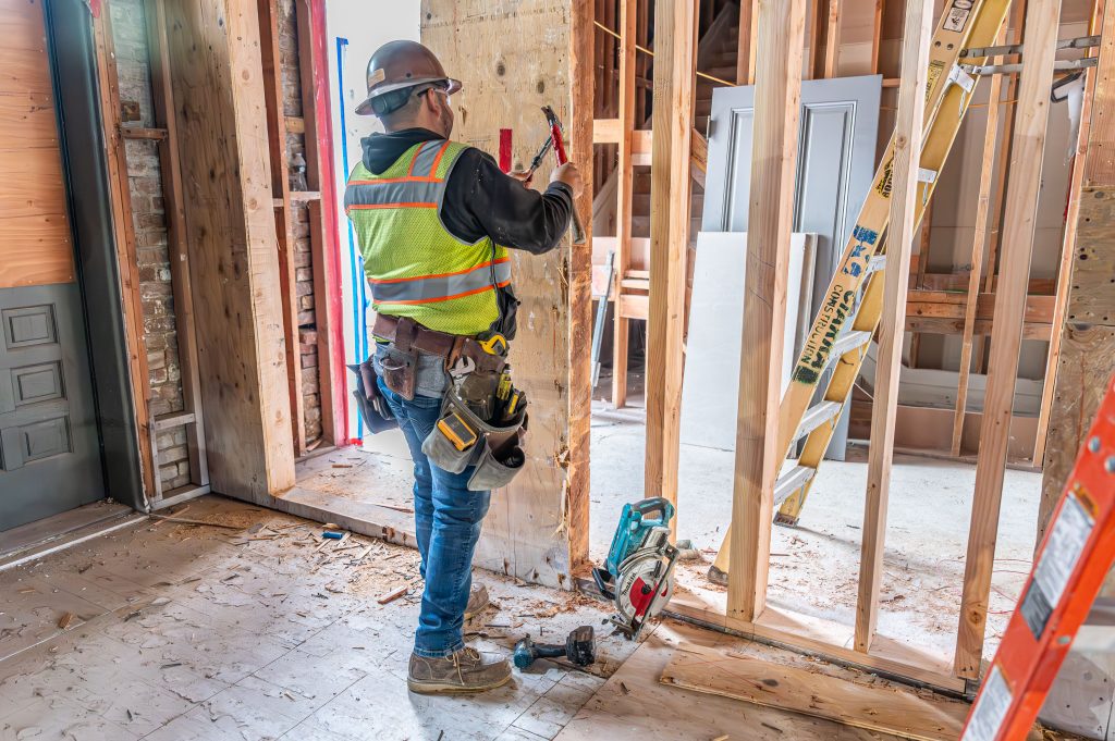 Carpenter measuring wooden boards for accurate framing of a new house