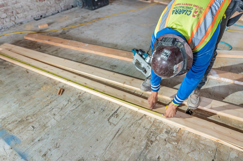 Man using a wrench to tighten bolts on wooden frame components.