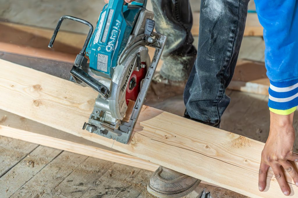 Construction worker applying wood glue to joints in a wooden frame