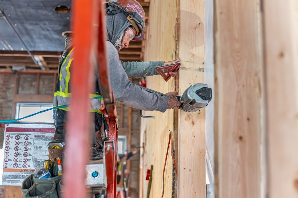 Person guiding wooden planks into place for constructing a building frame.