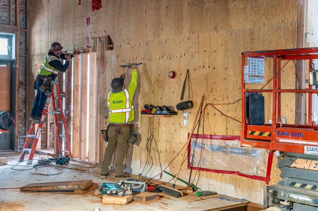 Builder in work boots lifting and positioning wooden frame components.