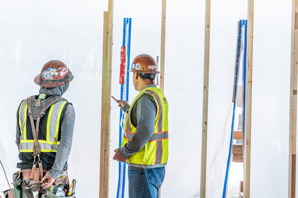 Construction worker measuring and cutting timber for a building frame
