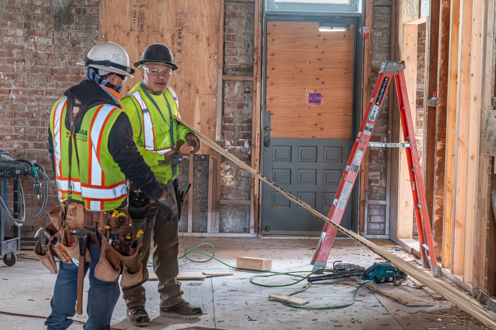 Person adjusting wooden beams to fit perfectly into the frame structure.