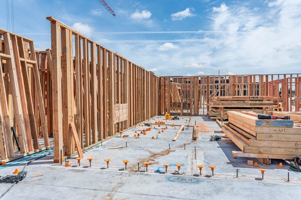 Construction worker using a clamp to hold wooden pieces together for framing.