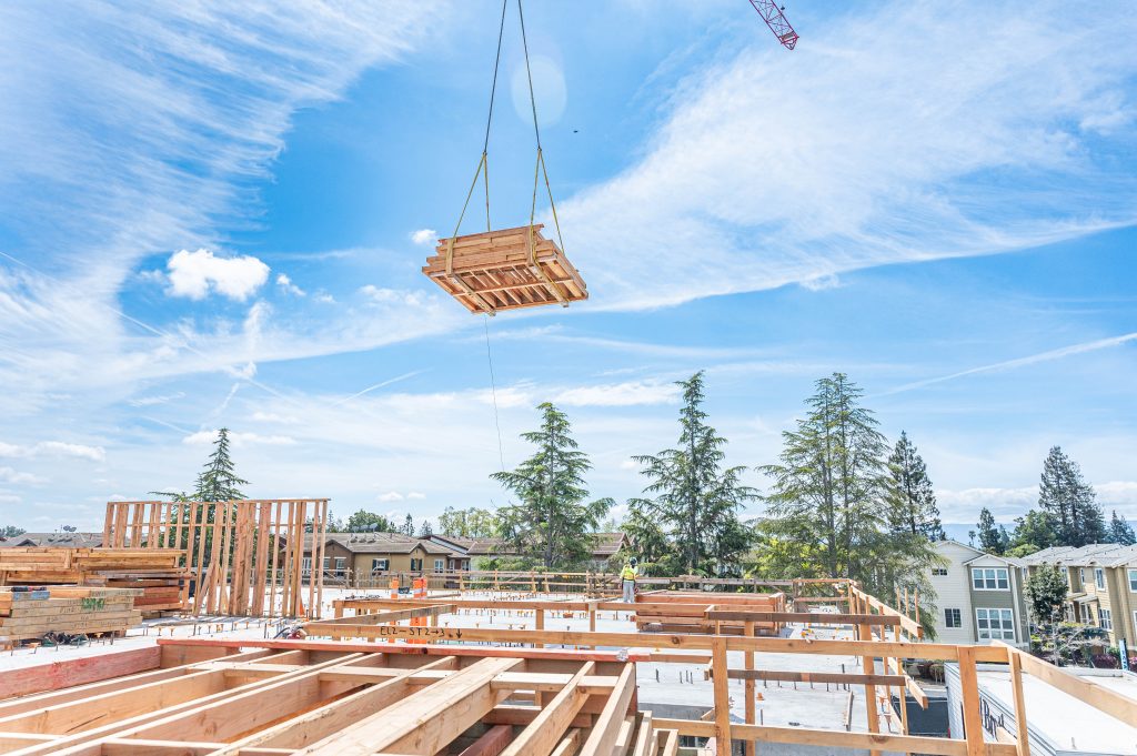 Carpenter aligning wooden beams and securing them with nails for stability