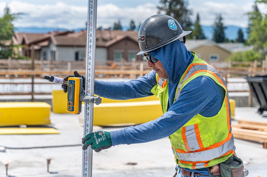Construction worker measuring and positioning wooden rafters for roofing