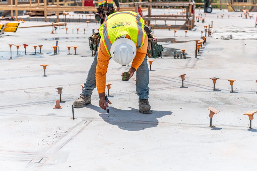 Builder in safety gear attaching wooden crossbeams to complete the frame