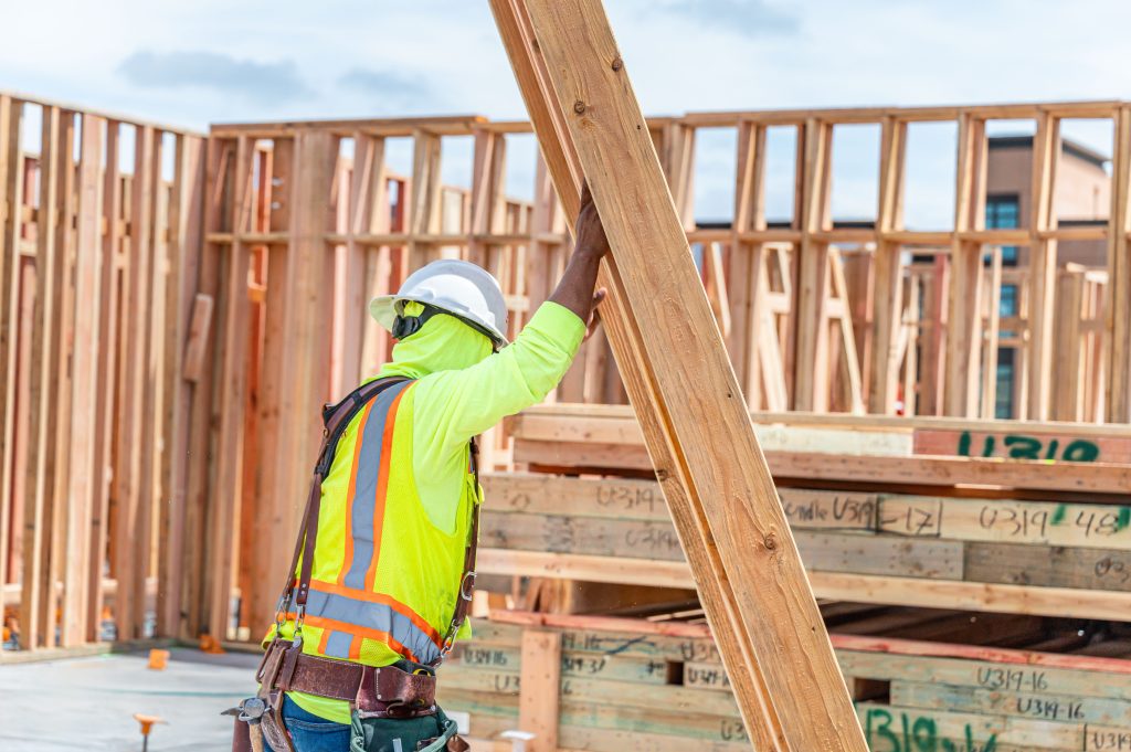 Carpenter using a power tool to fasten wooden components in a frame.
