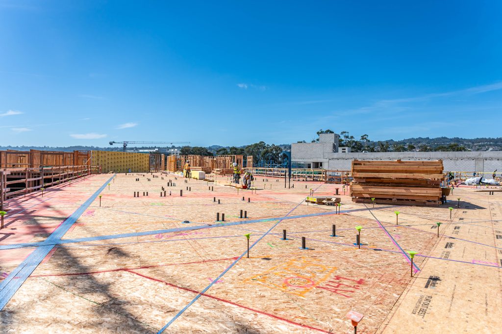 A bustling construction site with workers, equipment, and materials in motion, laying the foundation and framework for a new structure.