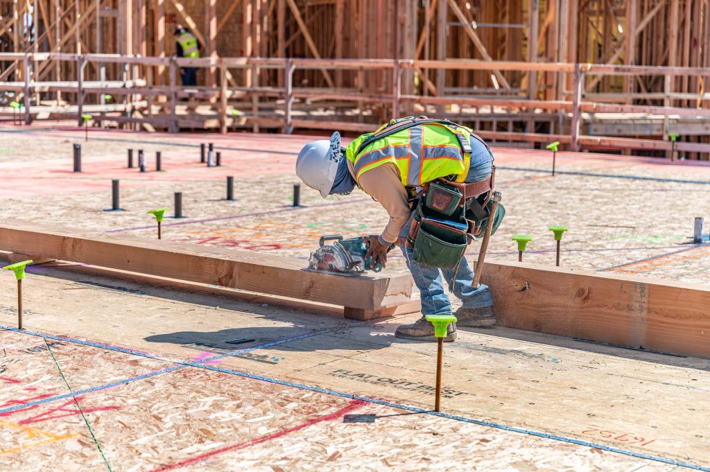 Carpenter working on framing a wooden structure with a power drill