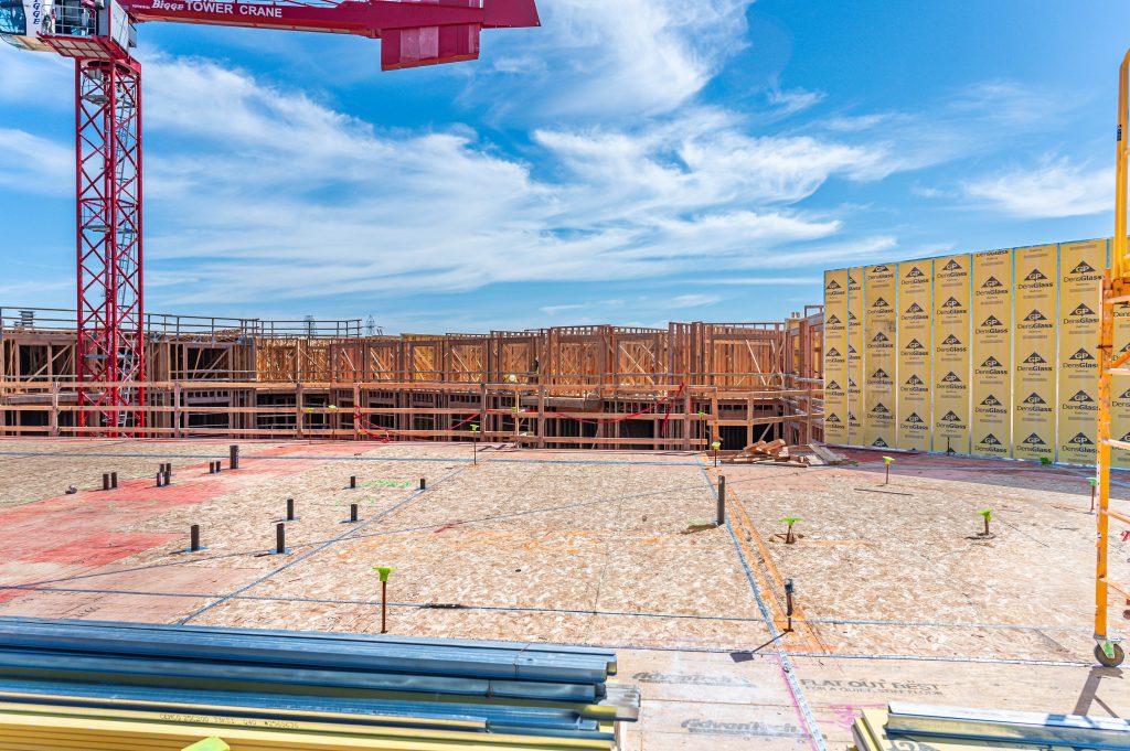 A wide view of a construction site, featuring machinery, scaffolding, and workers in safety gear actively building a structure.