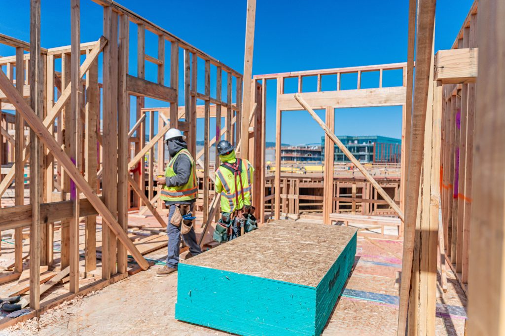 Construction site featuring a wooden building frame with diagonal bracing and vertical posts.