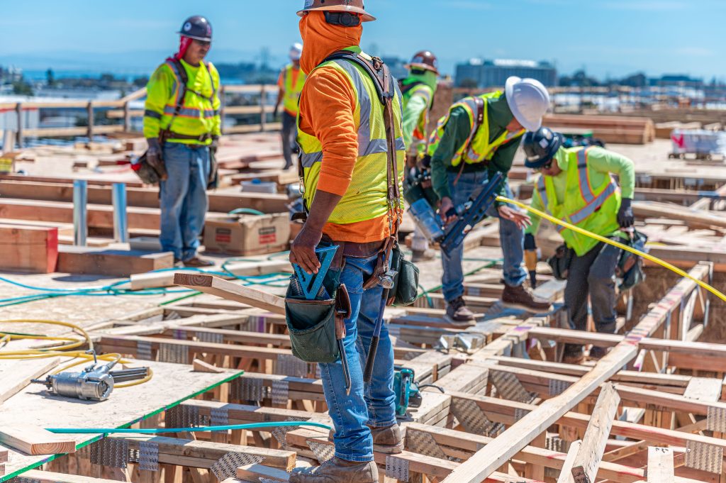 A team in a construction site working on assembling wooden wall frames.