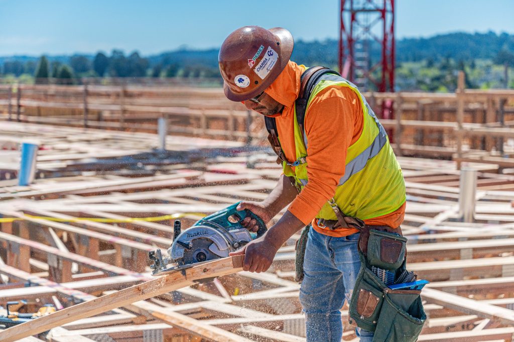 Person measuring and marking wooden beams for precise cutting