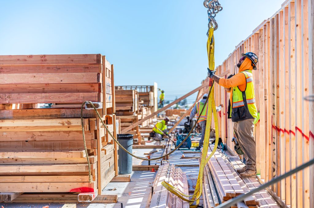 Construction worker in a hard hat guiding a wooden beam into place