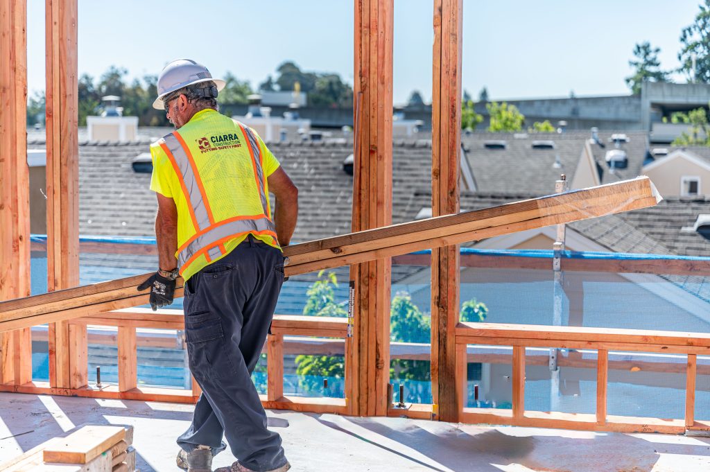 Man installing vertical wooden studs to build a wall frame
