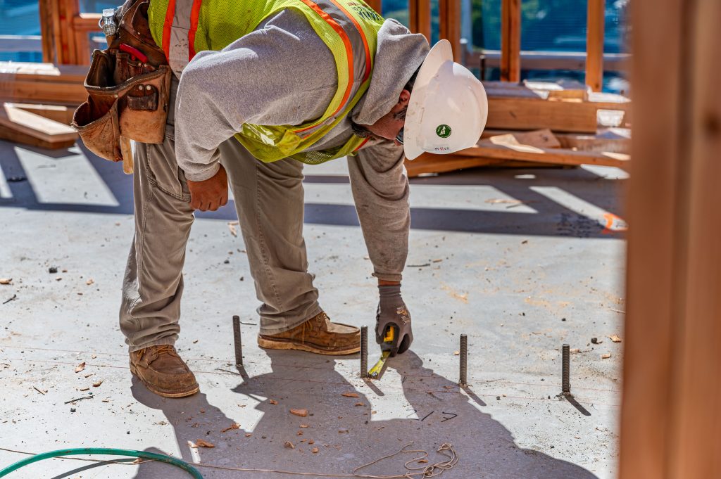 A construction worker wearing gloves measuring drilled holes in concrete
