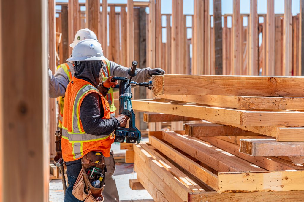 Man drilling holes in wooden beams to secure them in place