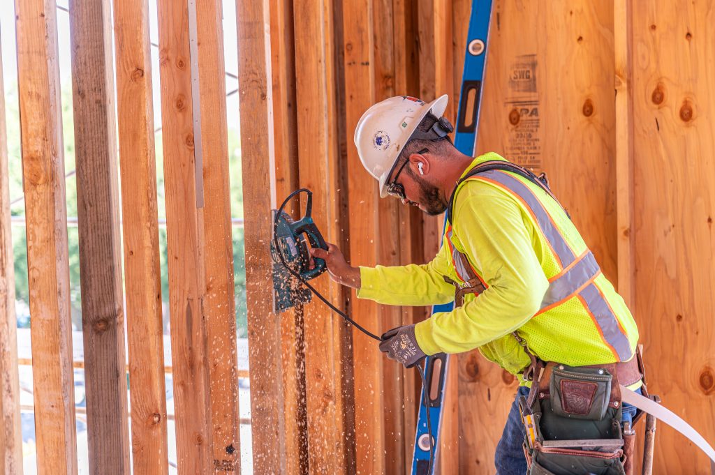 Construction worker framing a wooden structure on a building site.